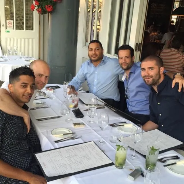 Five BTNDC members seated around a laid restaurant table with menus and cocktails